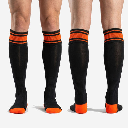 Men's custom orange and black soccer socks full-length profile view showing over the calf fit with orange stripe cuff and black body