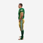 Second side view of custom green and gold football uniform set showing jersey hem, side panel continuity, and pant stripe alignment on a male player