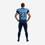 Left side view of sublimated football uniform set in sky blue and navy showing sleeve number 23 white cuff trim and full-length matching navy football pants