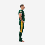 American football uniform packages in forest green and gold, side view showing wide gold pant stripe and white cuff trim on the sublimated jersey