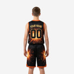 Left side view of black and gold youth basketball uniform showing orange V-neck trim and gold spark burst pattern flowing from jersey to shorts