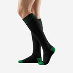 Angled view of custom black and green soccer socks displaying ribbed calf body and Kelly Green foot contrast zones
