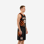 Custom black and orange basketball uniform front view showing arced team name and front number on sublimated jersey