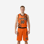 Front view of custom black and orange basketball uniforms with claw-scratch panel design, team name across chest, and matching shorts