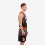 Side view of custom black and orange basketball uniform set showing orange lightning pattern on jersey side panel and matching shorts on a male model