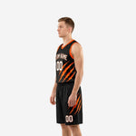 Side view of black and orange basketball uniform showing orange claw-mark graphic across jersey left panel and shorts outer leg