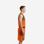 Side view of custom black and orange basketball uniform set showing claw-panel detail on jersey and shorts outer leg
