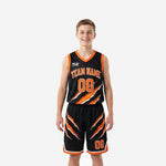 Black and orange youth basketball uniforms full set front view showing claw-slash graphic on jersey and matching shorts