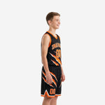 Side view of black and orange youth basketball uniform set showing V-neck jersey and claw-pattern shorts with orange hem band