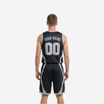 Side view of black and white reversible basketball uniform showing curved silver-grey panel running from armhole to hem on sleeveless jersey and matching shorts