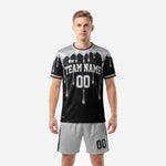 Custom black and white soccer uniforms with silver metallic drip graphic, full kit front view on male model showing team name and number print zones