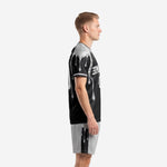 Black and silver custom soccer kit side view showing drip graphic cascading from silver crew neckline down jet black jersey body