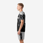 Custom black soccer kit side profile view displaying silver drip print continuing from jersey hem onto silver shorts waistband