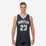 Black and white sublimation basketball jersey front view showing charcoal body, white side panels, arced team name, and front number 23 on adult male model