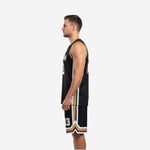 Side view of black and gold basketball uniform set showing geometric chevron side panels on the jersey and shorts