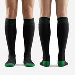 Full length view of custom black and green geometric soccer socks worn by adult male player