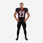 Custom football jersey and pants in black and red with arched team name, front number 23, red V-neck collar, and matching red-stripe football pants, front view