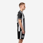 Black and white sublimated soccer uniform side view showing stripe detail on jersey and shorts