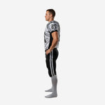 Side view of black panel American football uniform showing sleeve number, black side panel, and black pants with white leg stripes
