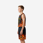 Side view of black and orange youth basketball uniform set showing armhole binding trim and flame pattern on shorts leg opening