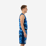 Side view of blue and white basketball uniforms showing digital-pixel camo pattern on jersey and shorts with navy V-neck binding and armhole trim