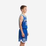 Side view of custom blue and white youth basketball uniform showing halftone dot pattern on jersey and shorts with white armhole binding and hem detail