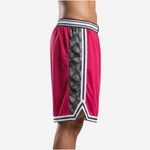 Red and black custom basketball shorts showing full geometric charcoal triangular side panel running from hip to hem with V-split at the hem - left side view