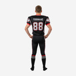 Left side view of sublimated youth football uniform set in black with red sleeve cuff trim and silver pant stripe