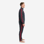 Side view of charcoal and crimson custom soccer tracksuit showing full-length Greek-key stripe from shoulder to ankle on jacket and pants
