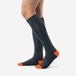 Angled view of over the calf charcoal and orange soccer socks showing ribbed cuff and calf panel