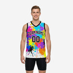 Colorful basketball jersey front and back view showing full-panel neon paint-splash sublimation on white with black V-neck binding and team name and number print