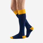 Angled view of custom navy blue soccer socks with Athletic Gold contrast cuff and toe cap on male model