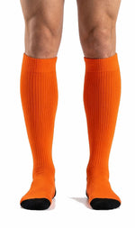 Custom Athletic Orange soccer socks front view showing ribbed calf knit and black contrast toe on male model