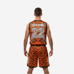 Second side view of orange and black custom basketball uniforms with logo showing claw mark graphic on lower shorts leg and black hem binding