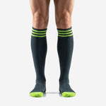 Custom black and green soccer socks front view showing charcoal body with triple neon green cuff stripes worn by male model
