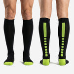 Custom black and green over the calf soccer socks worn by adult male showing full shin guard coverage and athletic fit