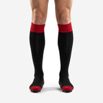 Custom black and red soccer socks with red ribbed cuff and red toe cap worn by adult male player front view