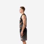 Side view of custom black basketball uniform showing gold-copper armhole binding, V-neck, and comet streak graphic running down jersey and shorts