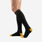 Custom black and gold soccer socks angled side view showing ribbed calf panel and gold toe cap detail on adult male model