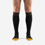 Custom black and gold soccer socks front view showing Athletic Gold diamond cuff band and Jet Black knee high body on adult male model