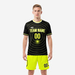 Custom black and yellow soccer uniform front view showing neon yellow concentric-circle graphic and matching neon yellow shorts on male model