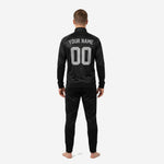 Close-up of custom black soccer tracksuit jacket showing stand collar, full-zip front, ribbed cuffs, and sublimated geometric-check pattern in jet black
