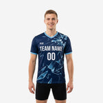 Custom blue soccer training jersey in Navy Blue and Ice Blue geometric shard print with team name and number on chest, worn by adult male model, front view