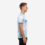 Custom blue and white training jersey left side view showing full-dye sublimation branch pattern on sleeves and hem