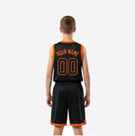 Opposite side view of black and orange youth basketball uniform set showing armhole binding and shorts side accent panel