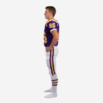 Left side view of youth American football uniforms in purple and gold showing the full-length pant stripe and D-ring belt area