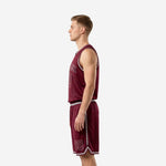 Side view of custom burgundy basketball uniform showing silver armhole binding sleeveless jersey and shorts with silver side stripe and hem detail