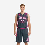 Custom charcoal basketball uniforms with hot-pink lightning fracture pattern on shoulders, arced team name, and matching shorts - front view