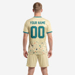 Detail view of terrazzo splash print on custom cream men's soccer jersey with teal team name and number across chest