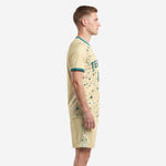 Custom cream soccer outfits men side view showing teal sleeve cuff trim and terrazzo print pattern on jersey and shorts